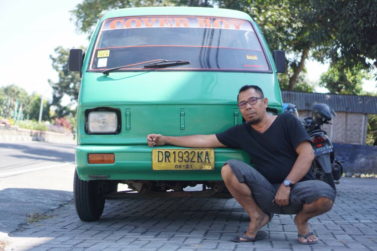 BERSAMA SI PLAT KUNING TUA: Zakaria, sopir angkutan umum berfoto di depan mobil tuanya di depan terminal Pancor, belum lama ini. (Dok Lombok Post)