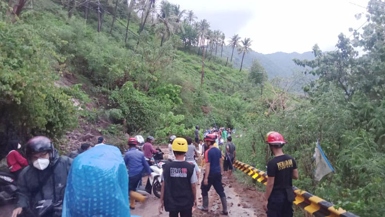 BERSIHKAN MATERIAL LONGSOR: Tim gabungan BPBD KLU, TRC PB, Barasiaga, TNI, hingga masyarakat membersihkan material longsor di badan jalan raya Senggigi-Pemenang, Senin (17/10). (Foto: BPBD KLU)