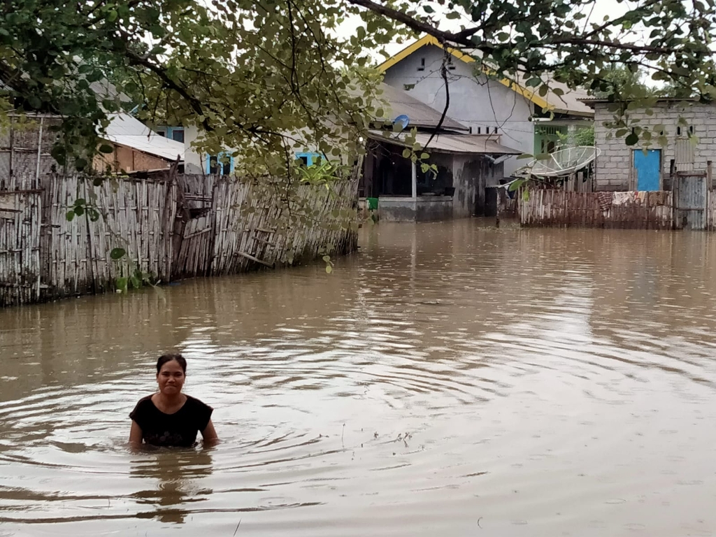 BANJIR: Seorang warga di perumahan nelayan Kampung Baru, Desa Tanjung Luar, Kecamatan Keruak sedang melewati genangan air setinggi dada orang dewasa yang membanjiri rumahnya, belum lama ini. (Subhan for Lombok Post)