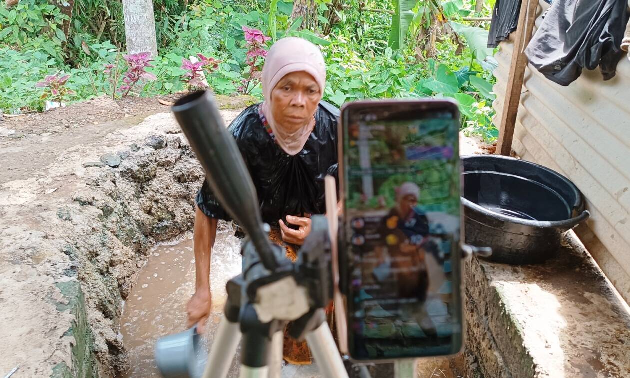 LIVE TIKTOK: Inaq Jumawardi, salah satu pemeran konten TikTok nenek mandi lumpur dan mandi tengah malam di Dusun Pedek, Desa Setanggor, Praya Barat, Loteng saat live, Kamis (19/1). (Dedi/Lombok Post)