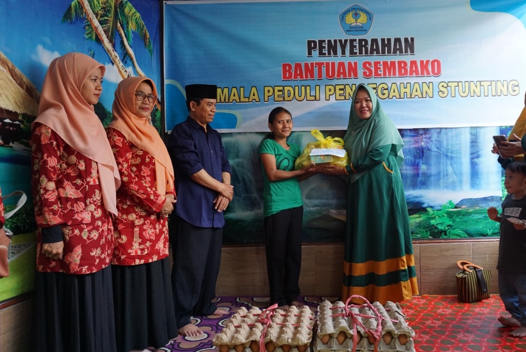 LANGKAH PENCEGAHAN: Kepala SMAN 5 Mataram H Siti Nurhani (dua dari kanan) memberikan sumbangan kepada salah satu warga, dalam kegiatan Smala Peduli Pencegahan Stunting, Jumat (13/1). (SMAN 5 Mataram for Lombok Post)