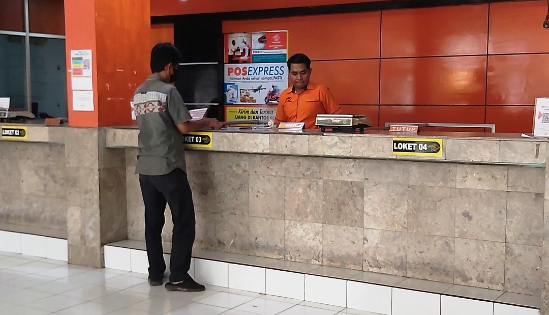 BAYAR-BAYAR: Seorang pelanggan pos melakukan pembayaran transaksi di loket Kantor Pos Mataram.(NURUL/LOMBOK POST)