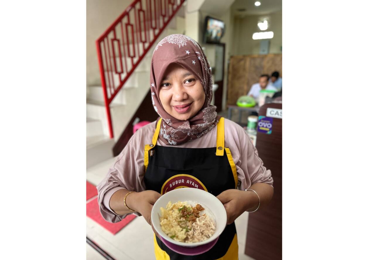 MENU ANDALAN: Owner Bubur Ayam 43 Mataram Etna Rita menunjukkan menu andalan bubur ayam komplit di outletnya, beberapa hari lalu.(NURUL/LOMBOK POST)