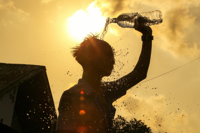 HILANGKAN PANAS: Seorang pemuda membasahi kepalanya dengan air untuk mengurangi suhu udara yang panas, Selasa (25/4). (Ivan/Lombok Post)