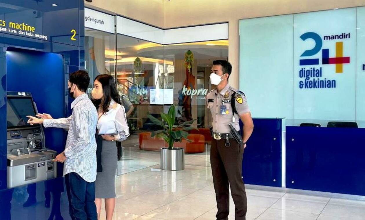 ARAHKAN: Seorang CS Mandiri Gde Ngurah Cakranegara membantu nasabah yang akan cetak ATM. (NURUL/LOMBOK POST)