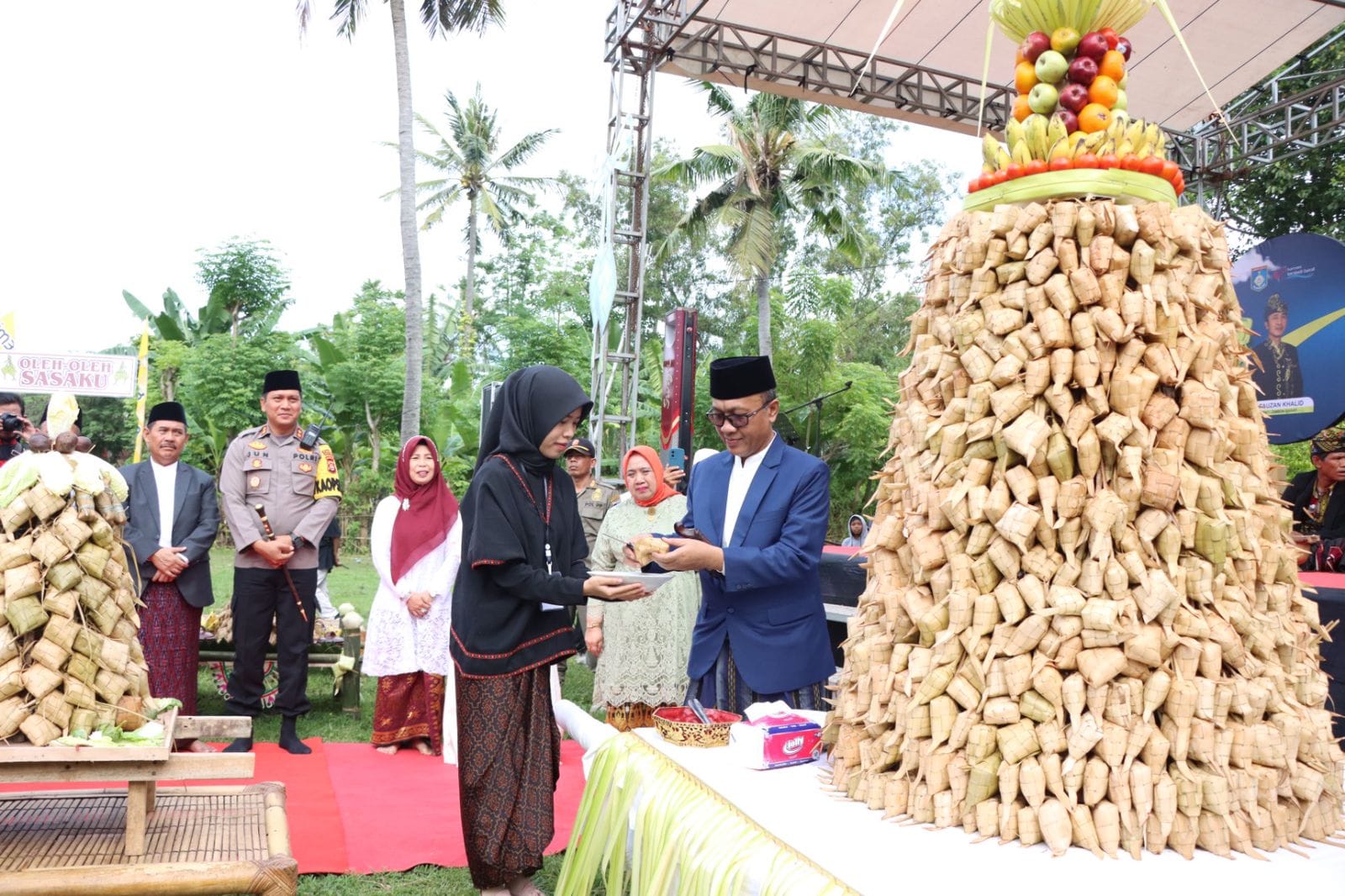 KEBANGKITAN SENGGIGI: Bupati Lobar H Fauzan Khalid menerima potongan gunugan ketupat saat perayaan Lebaran Topat di Pantai Duduk 3, Senggigi, Sabtu (29/4).
