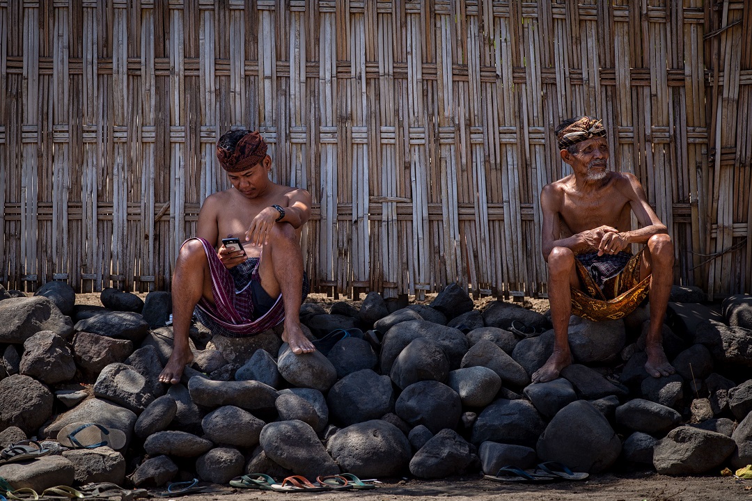 JANGKAU DUNIA: Seorang warga desa adat Bayan, Lombok Utara berselancar di dunia maya menggunakan smartphone miliknya.(IVAN/LOMBOK POST)