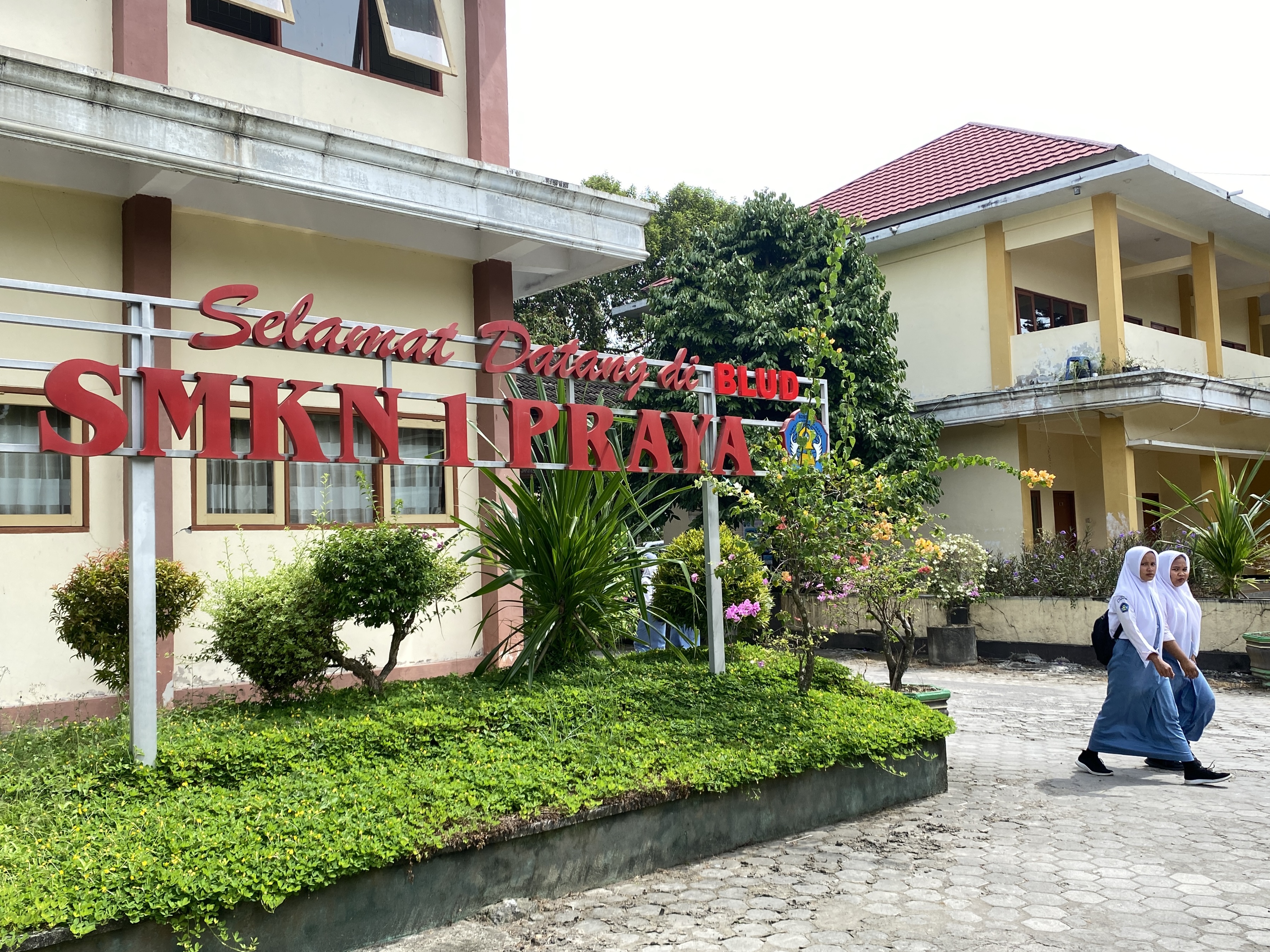 CIRI KHAS SEKOLAH: Dua siswi melintas di halaman depan BLUD SMKN 1 Praya, Selasa (9/5). (Yuyun/Lombok Post)