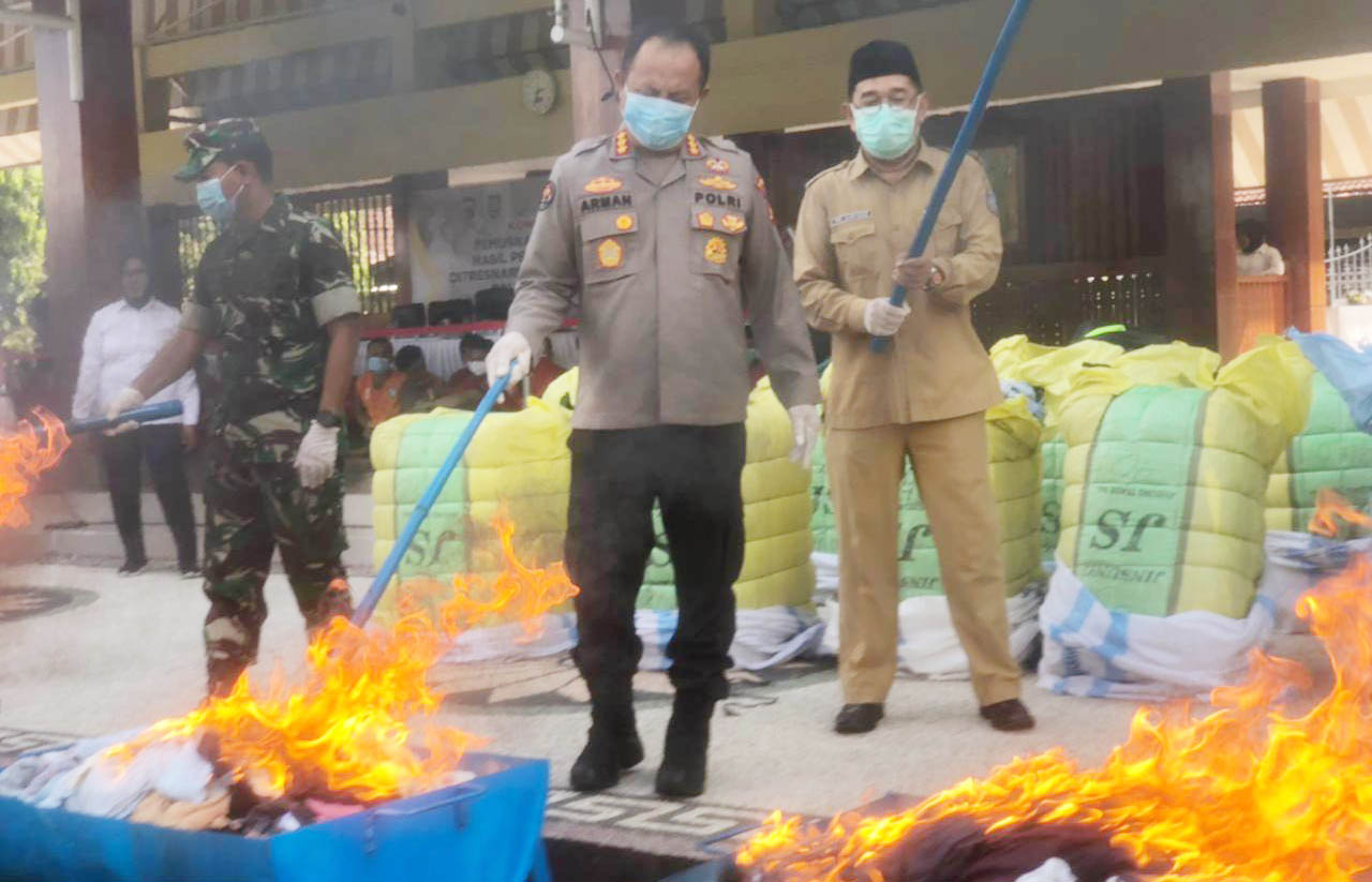 DIBAKAR: Kabid Humas Polda NTB Kombespol Arman Asmara Syarifuddin (tengah) bersama pihak terkait saat membakar pakain bekas impor di Lapangang Bhara Daksa Polda NTB, Senin (8/5). (Toni/Lombok Post)