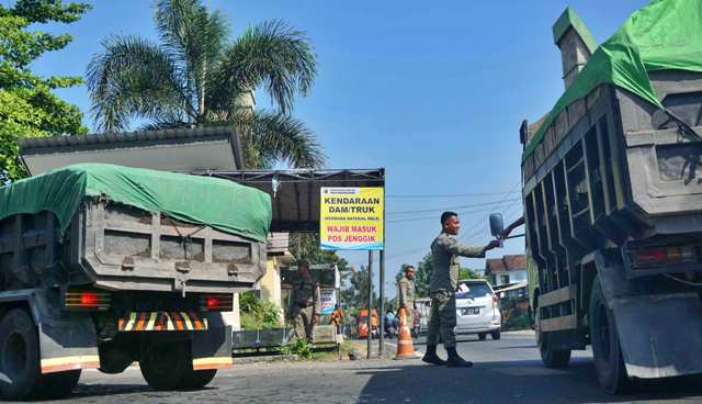 TERIMA BUKTI: Petugas jaga truk pengangkut MBLB Satpol PP Lotim menerima bukti pembayaran dari sopir truk di pos perbatasan Jenggik, Kecamatan Terara, Jumat (19/5). (Fatih/Lombok Post)