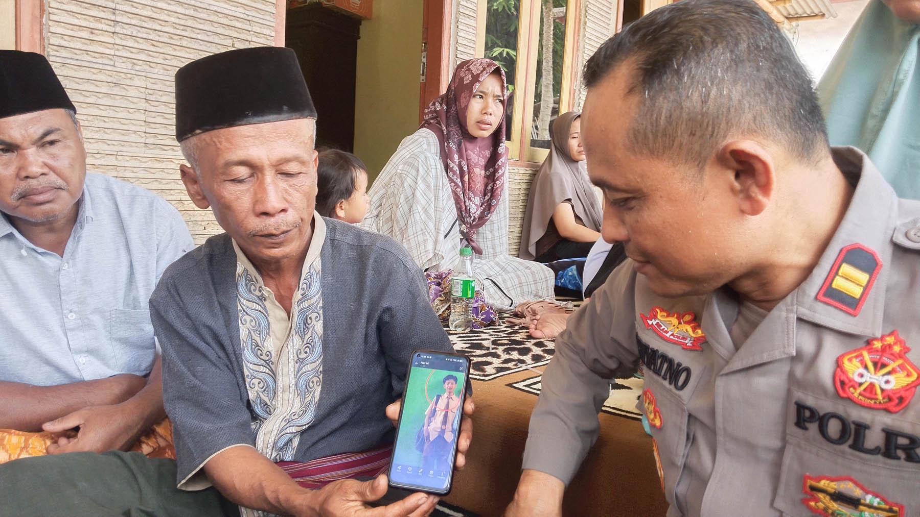 JADI PELAJARAN: Sahnun didampingi Kapolsek Praya Tengah Iptu Prayitno menunjukkan foto almarhum Rian Adriansyah semasa hidup di rumah duka Dusun Tambun, Desa Pengadang, Kecamatan Praya Tengah, Loteng, Kamis (3/8). Foto: Dewi/Lombok Post.