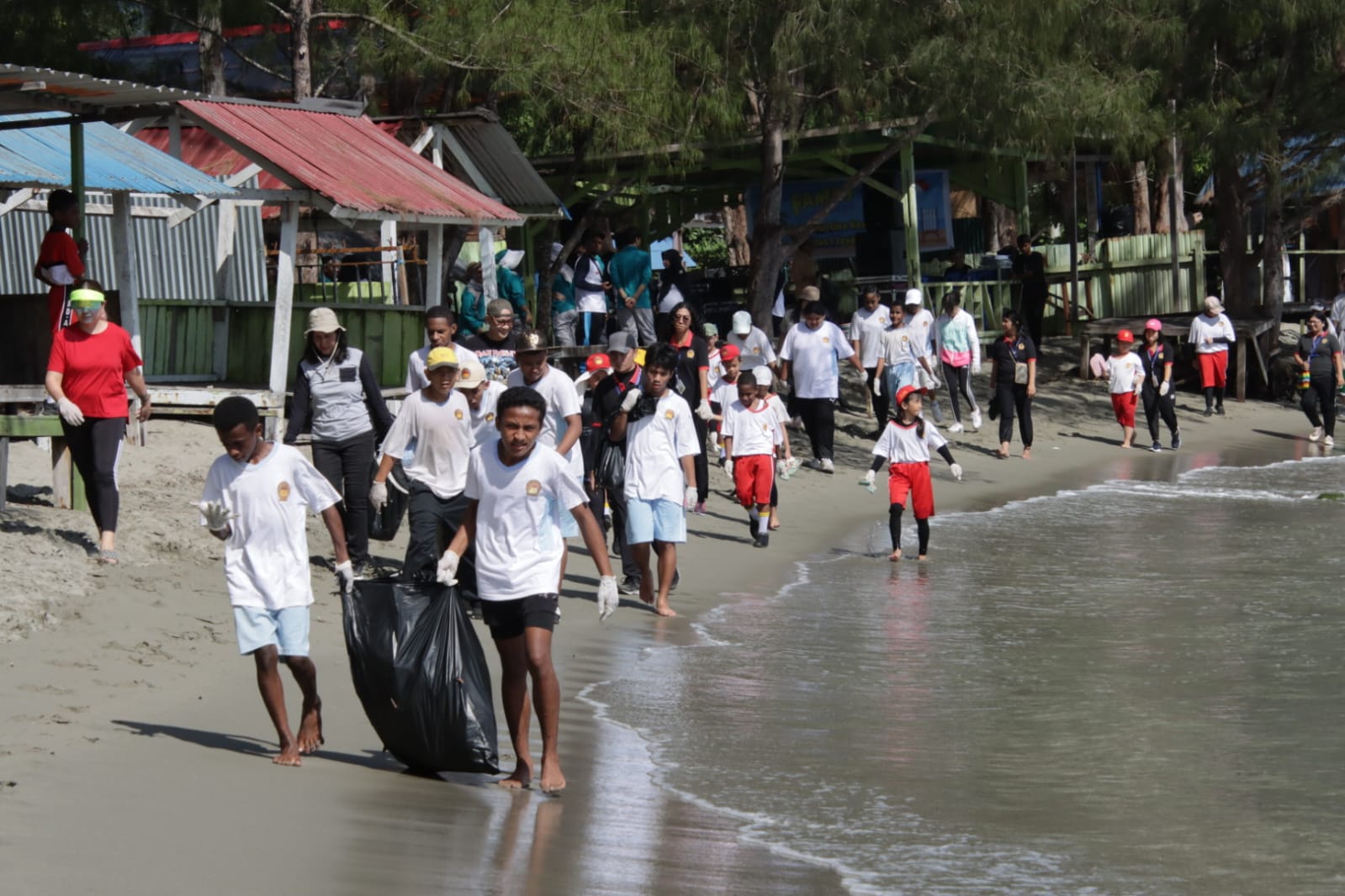 Para peserta didik dari Papua National School didampingi para guru ketika memungut sampah di Pantai Hamadi, Jayapura, Kamis, (7/3/2024).