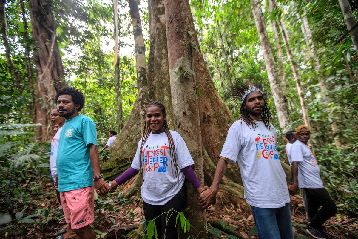Kelompok pemuda dan masyarakat adat berdiri mengelilingi sebuah pohon disalah satu hutan di Papua belum lama ini. Ini sebagai simbol memproteksi hutan yang dimiliki. (Foto : GPI For Cepos)