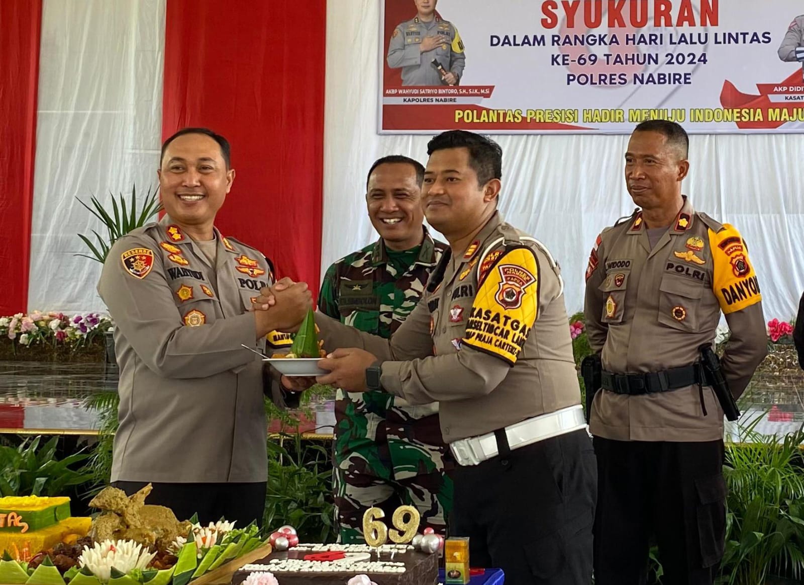 Kapolres Nabire Wahyudi Satriyo saat menyerahkan potongan tumpeng kepada kasat lantas dalam HUT Lantas ke 69 di Polres Nabire, Jumat (20/9).&nbsp;(CENDERAWASIH POS/Theresia F. Tekege)