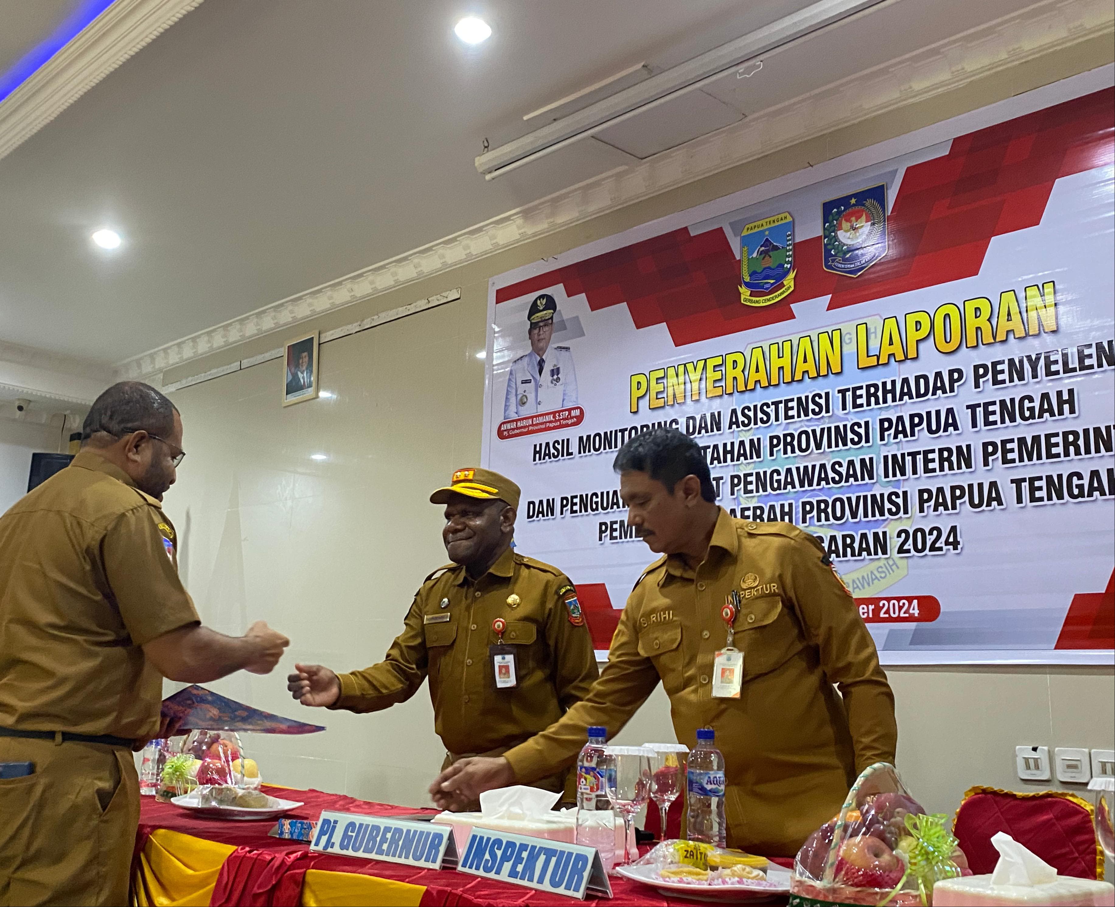 Asisten I Bidang Papteng, Menase Kadepa didampingi Inspektur Inspektorat Papua Tengah, Samuel Rihi menyerahkan dokumen hasil monitoring dan penguatan APIP kepada Kepala Bapperinda Papteng, Eddy Way.