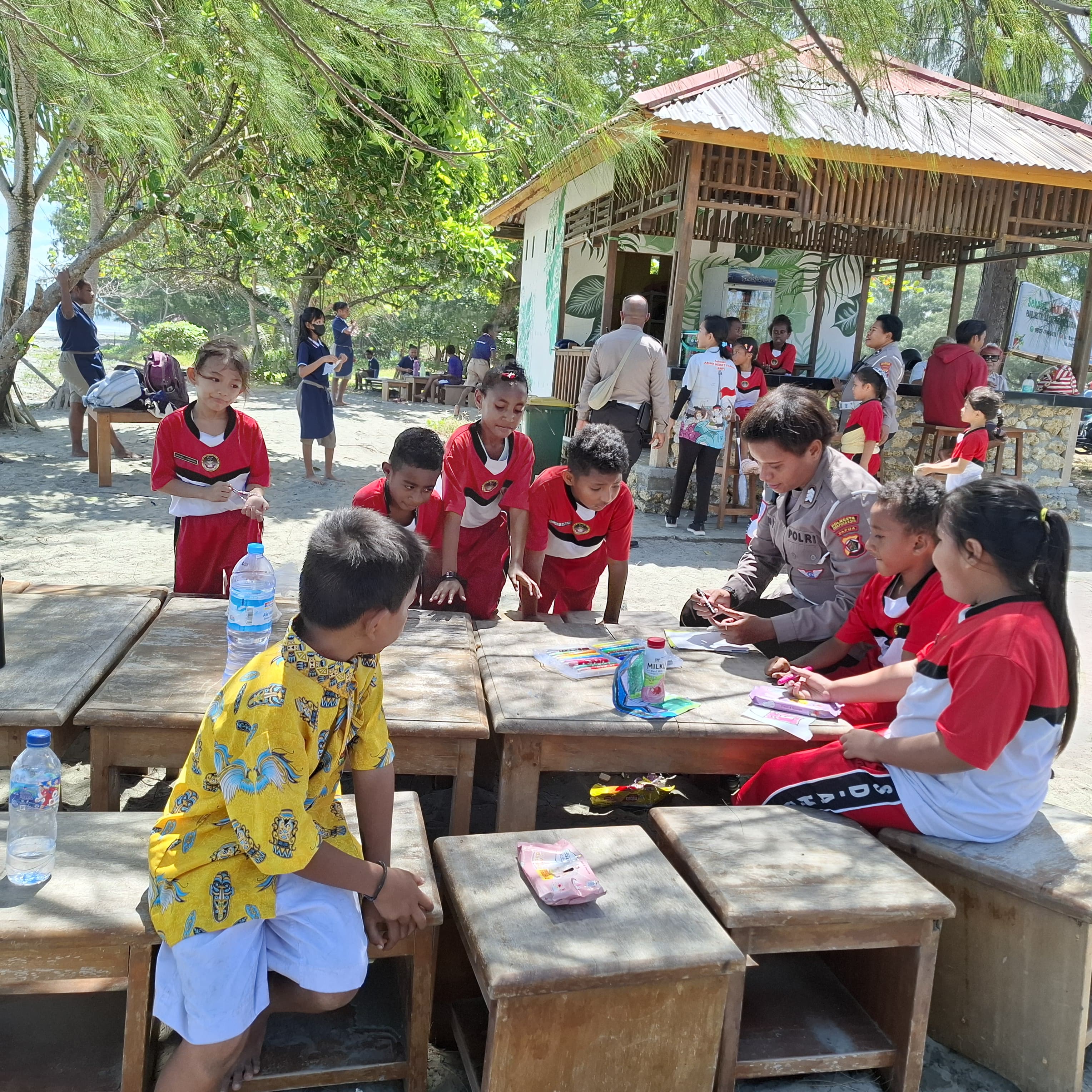Salah satu anggota Polwan ketika mengajarkan kepada anak-anak sekolah pada program taman baca Polresta di Pantai Holtekam, Kamis (16/1/2025) (Foto: Humas Polresta).