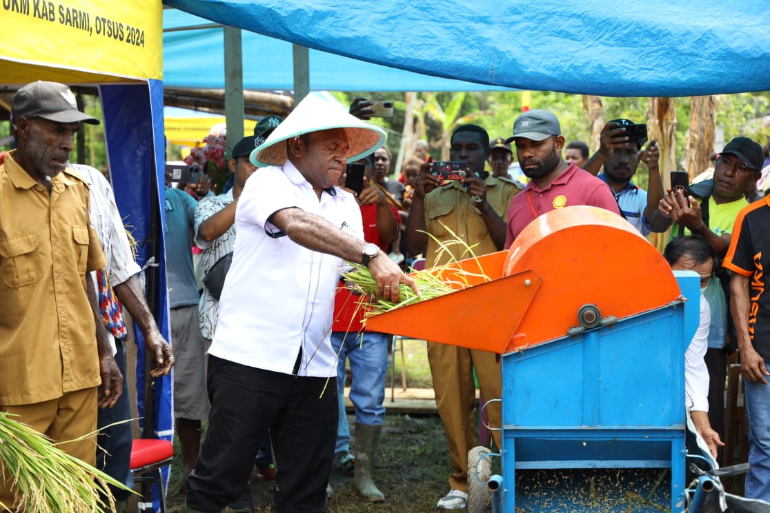 Bupati Sarmi Dominggus Catue SKM.Mkes mencoba menggunakan mesin perontok padi, usai melakukan penen raya padi di Kampung Mengke, Distrik Pantai Timur Barat, Rabu (9/4/42025) :HUMAS/ceposonline.com