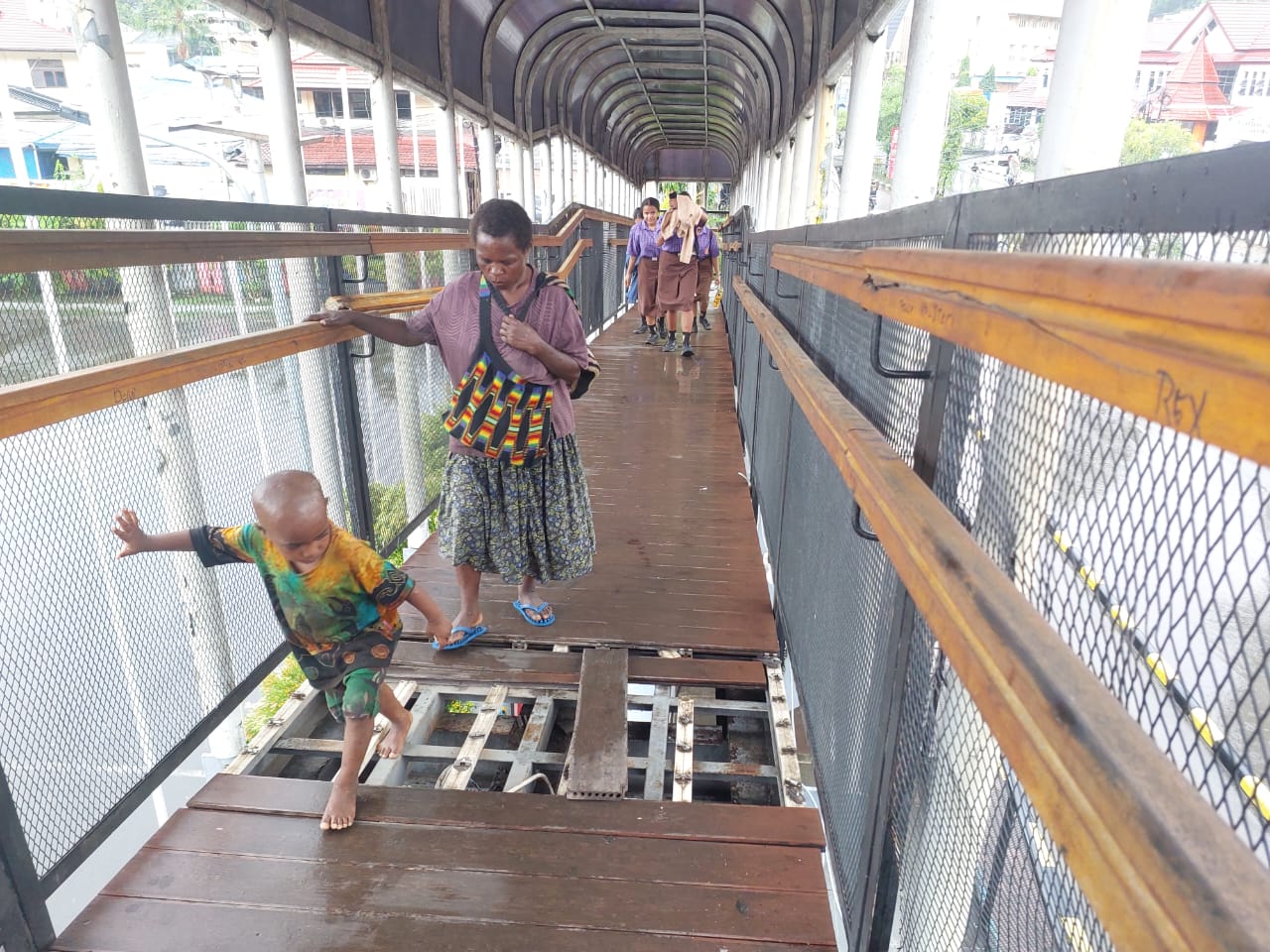 Masyarakat saat melintasi JPO yang terletak di depan Mall Jayapura, yang kondisinya rusak pada Rabu (7/5/2025). (CEPOSONLINE.COM/KAREL)