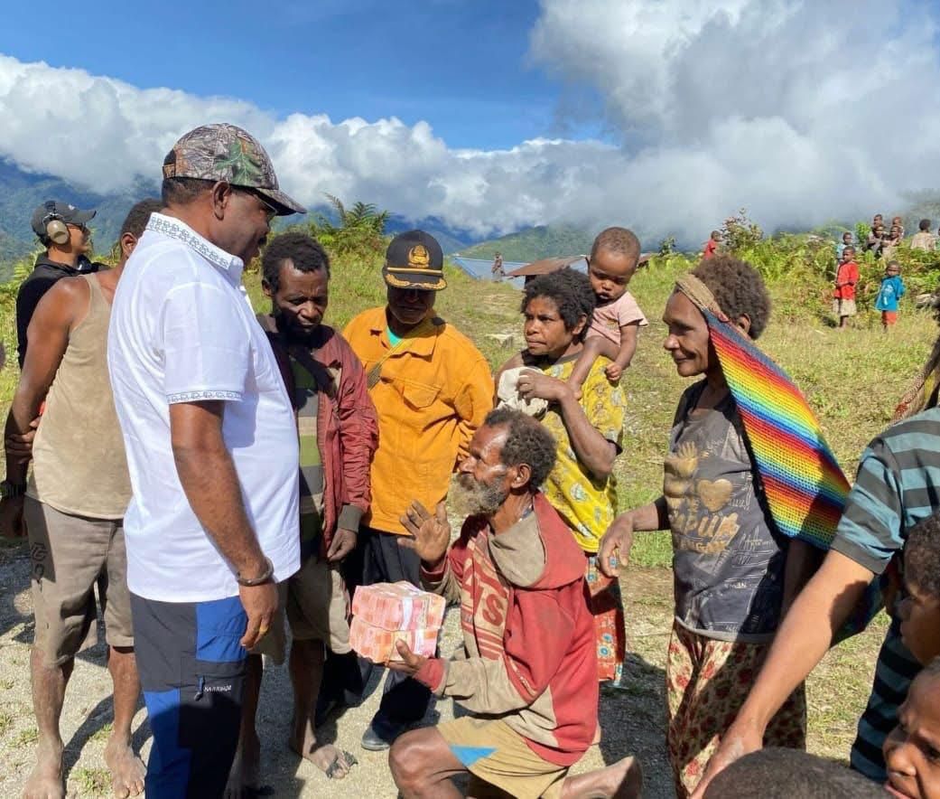 Bapak Pewarta Yakob Wakei di Kampung Jigikebo sedang berlutut dan mendoakan Bupati Nabire Mesak Magai saat menerima bantuan dana untuk peresmian Gereja Katolik. (CEPOSONLINE.COM/THERESIA F. TEKEGE)
