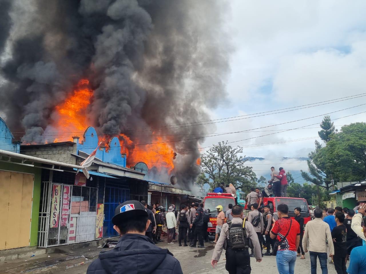 Aparat kepolisian bersama Petugas Damkar Pemkab Jayawijaya saat berupaya untuk memadamkan api yang membakar 6 rumah asrama Polres Jayawijaya dan 9 ruko di perempatan Pramuka Wamena, Jumat (21/11/2025)