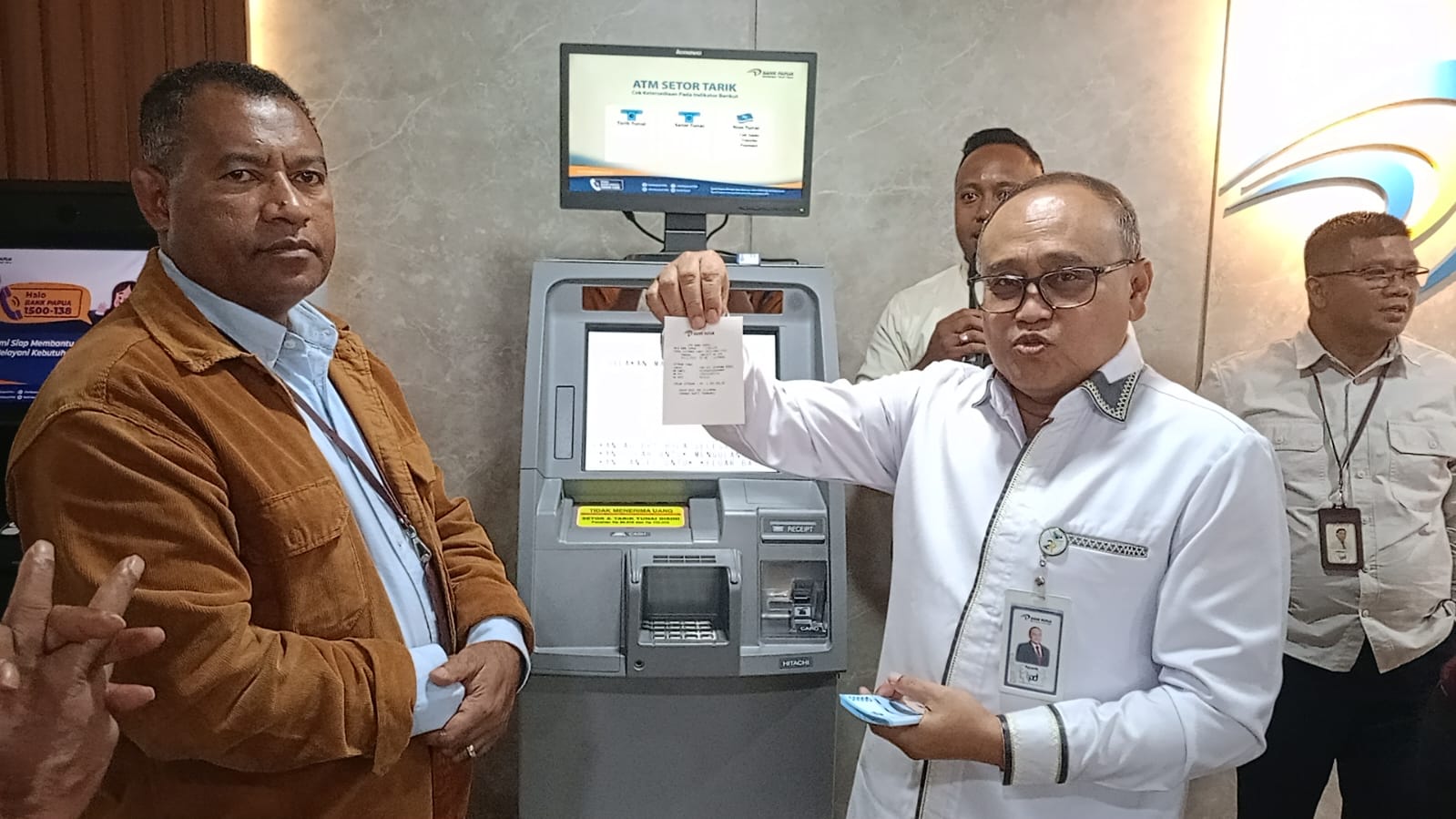 Direktur Operasional Isak S.Wopari dan Direktur Keuangan Pujianto, melakukan simulasi penggunaan ATM CRM dan berhasil disaksikan Pemimpin Divisi dan Pemimpin Cabang KCU Jayapura dalam launching Mesin