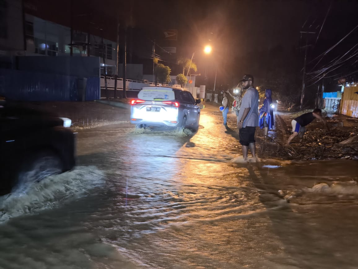 Para pemuda di Entrop membantu mengatur arus lalu lintas di depan CV Thomas Entrop, saat air naik ke badan jalan akibat banjir, Kamis (11/12025).(Ceposonline.com/Istimewa)