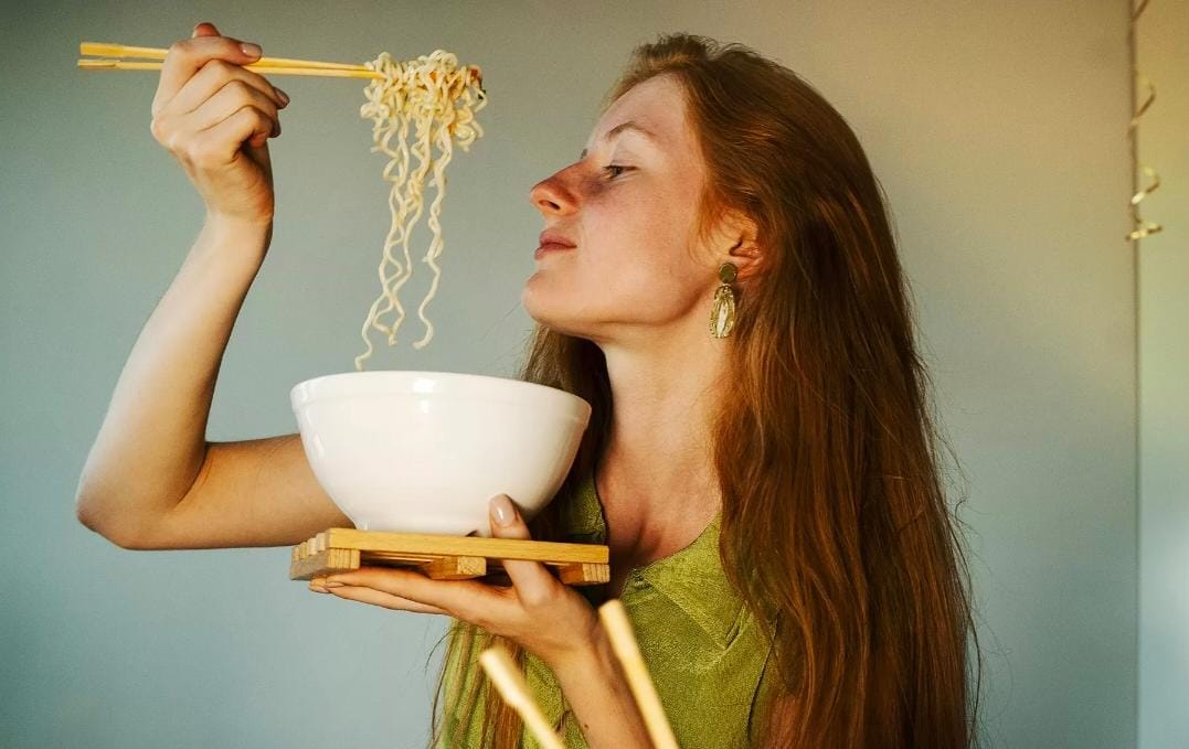 Ilustasi seorang perempuan makan mie instan. (Dok. Freepik/JAWAPOS)