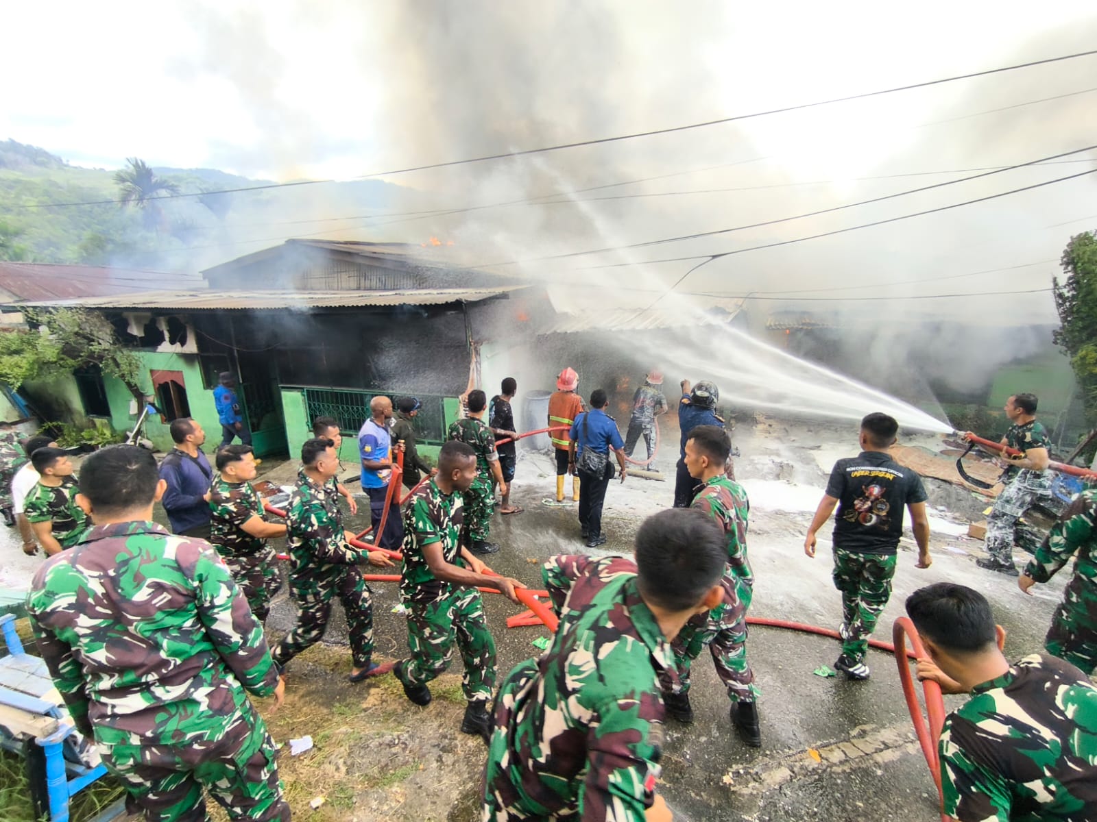 Puluhan Prajurit TNI bergotong royong menyiramkan air pada barisan rumah yang terbakar, Selasa (10/3/2026). (CEPOSONLINE.COM/GAMEL)   