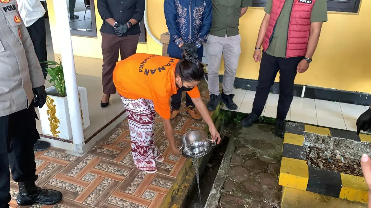 Tersangka sedang menuangkan barang bukti sabu yang telah dilarutkan ke dalam satu panci air panas, dalam kegiatan pemusnahan barang bukti narkotika di Mako Polres Mimika, Papua Tengah, Kamis (4/6/2026).(CEPOSONLINE.COM/MOH. WAHYU WELERUBUN).