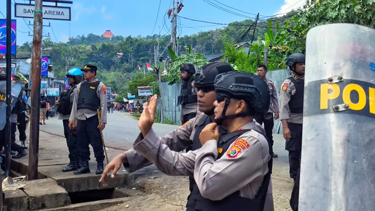 Dua perwira Polisi saat berkoordinasi di depan lorong di Perumnas III Waena yang menjadi satu lokasi saling lempar antara aparat dan pendemo, Sabtu (15/8/2026). (CEPOSONLINE.COM/GAMEL) 