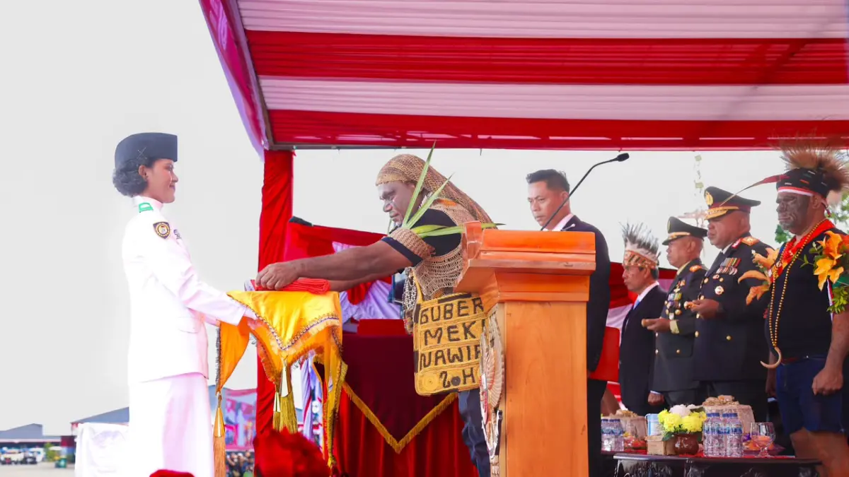 Gubernur Papua Tengah, Meki Nawipa saat menyerahkan bendera Merah Putih kepada pembawa baki dalam upacara peringatan HUT RI ke - 81 di Papua Tengah. (CEPOSONLINE.COM/HUMAS PEMPROV)&nbsp;