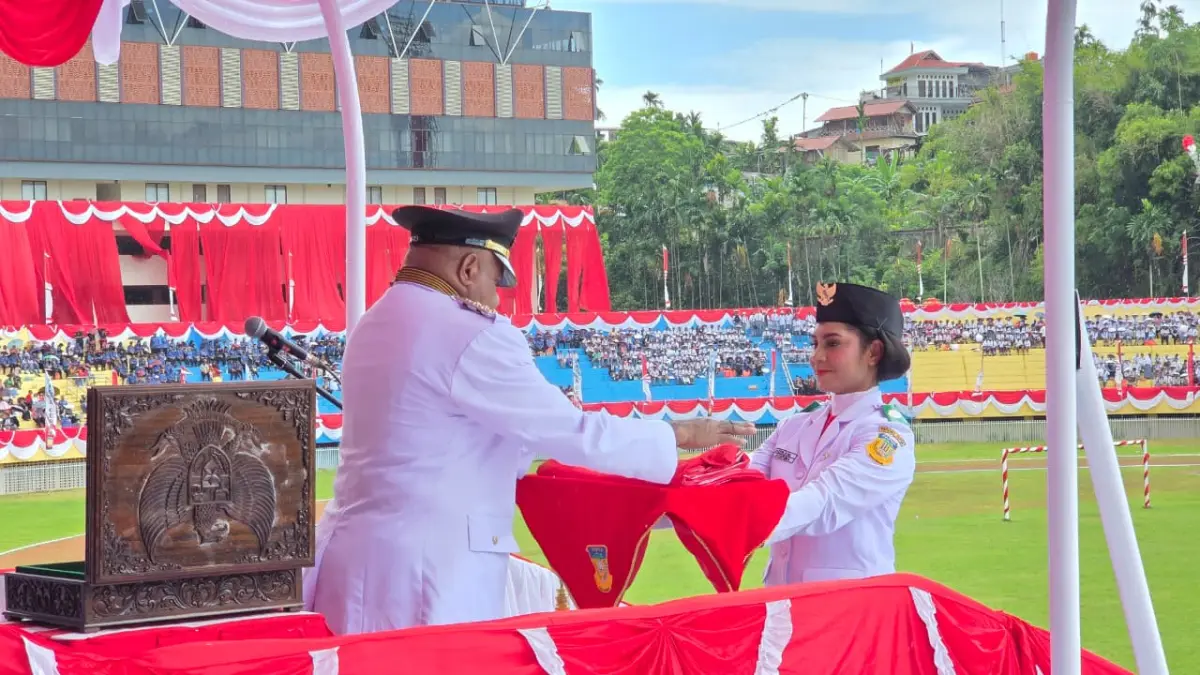Pembawa baki, Glory Adadikam menerima bendera Merah Putih dari Gubernur Papua, Matius D Fakhiri pada upacara peringatan 17 Agustus di Lapangan Mandala, Senin (17/6/2026). (CEPOSONLINE.COM/ELFIRA)