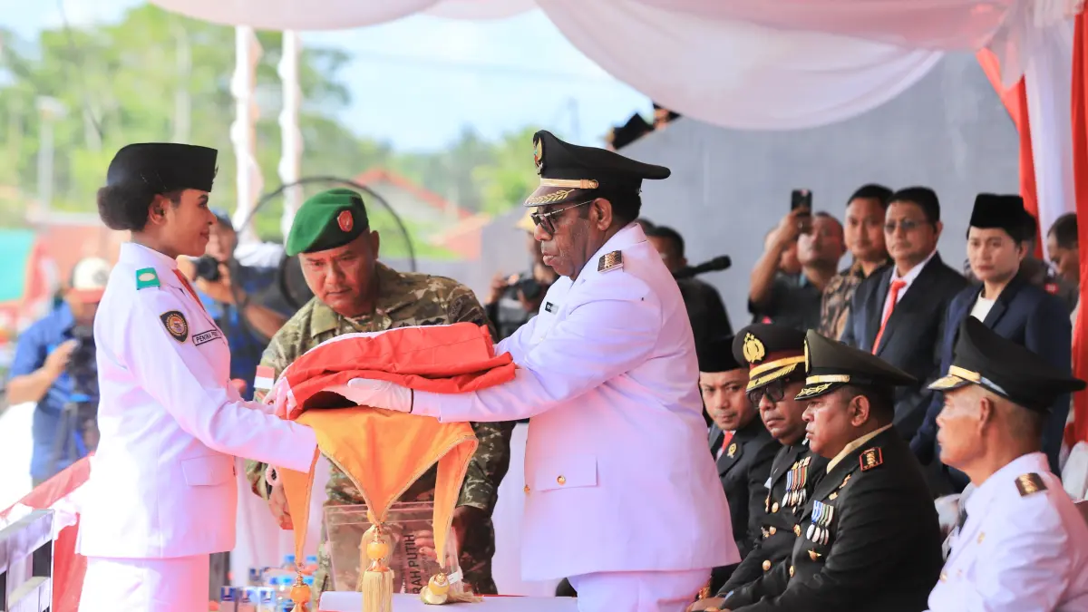 Bupati Keerom, Piter Gusbager saat menyerahkan bendera merah putih kepada Paskibraka pembawa baki bendera dalam upacara peringatan HUT ke-81 RI di Lapangan Swakarsa, Kampung Asyaman, Distrik Arso, pada Senin (17/8/2026). (CEPOSONLINE.COM/ERIANTO).