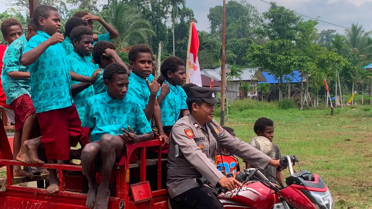 Seorang aparat kepolisian menggunakan kendaraan roda tiga mengantar anak-anak sekolah di Kapiraya, Mimika, Papua Tengah. (Foto: Istimewa).&nbsp;