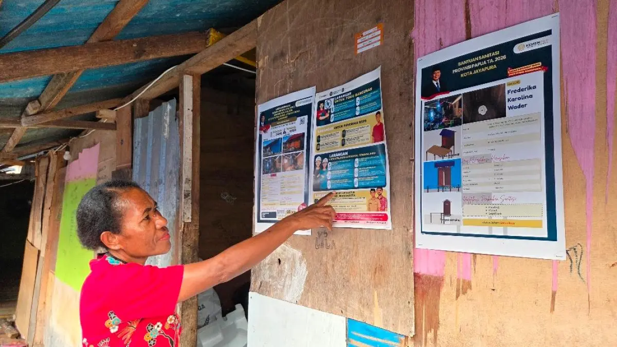 Penerima BSPS di Dok IX Tanjung Ria, Kota Jayapura, Papua, Fedrika Karolina Wader saat memperlihatkan brosur yang mencantumkan program BSPS Tahun Anggaran 2026 di dinding rumahnya, Kamis (27/8).(CEPOSONLINE.COM/ELFIRA).