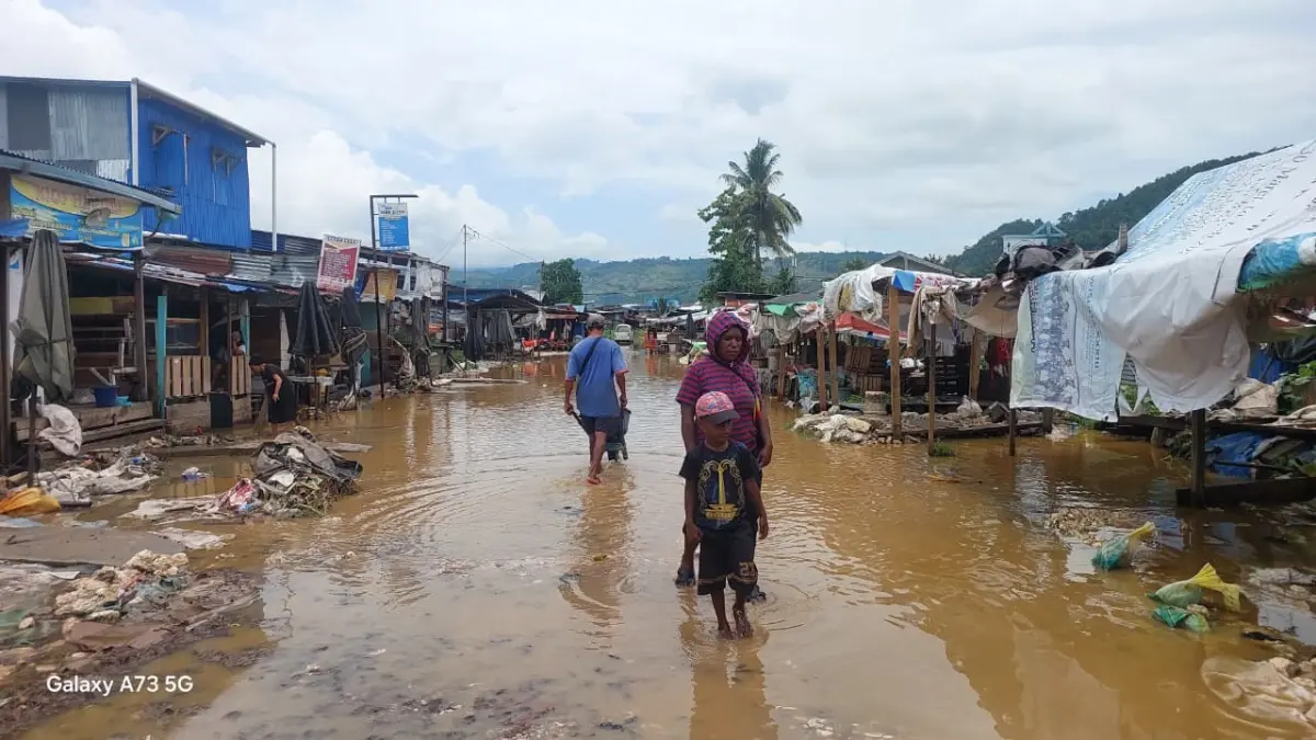 Seorang ibu dan anaknya ketika melintasi di genangan air yang terjadi saat banjir di Pasar Yotefa, Selasa (22/9/2026).(CEPOSONLINE.COM/KAROLUS DAOT)