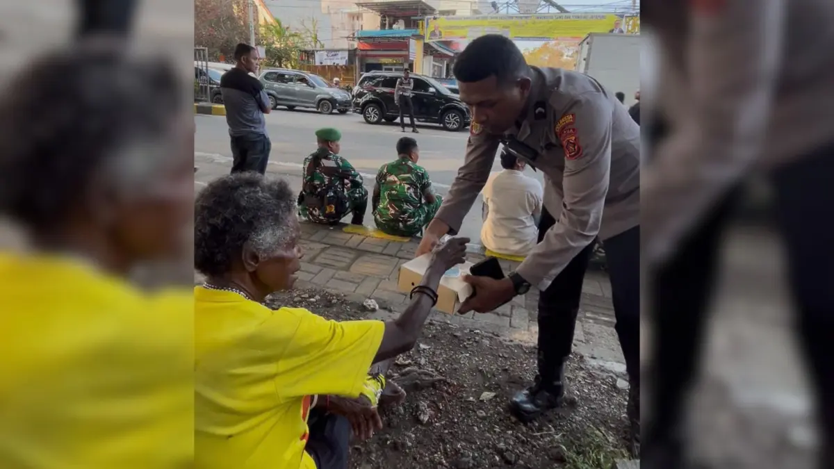 Bripda Robert Awek saat memberikan nasi kotak kepada seorang lansia yang terjebak aksi massa di USTJ Padang Bulan, Rabu (30/9/2026)

(Foto: Paed For Cepos)