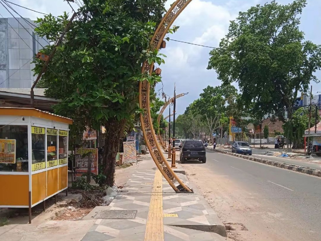 TAK SESUAI: Penerangan jalan umum (PJU) di trotoar Jalan Hadji Boejasin dikritik karena menghalangi jalur disabilitas.
