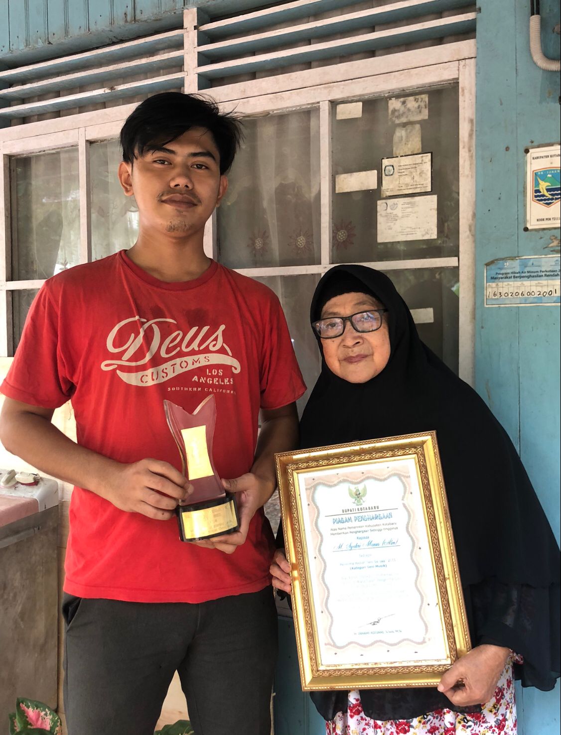 BERBAHAGIA: Nursehan dan Rifki, istri dan anak M Syukri Munas dengan bangga memperlihatkan piagam penghargaan yang pernah diraih almarhum.