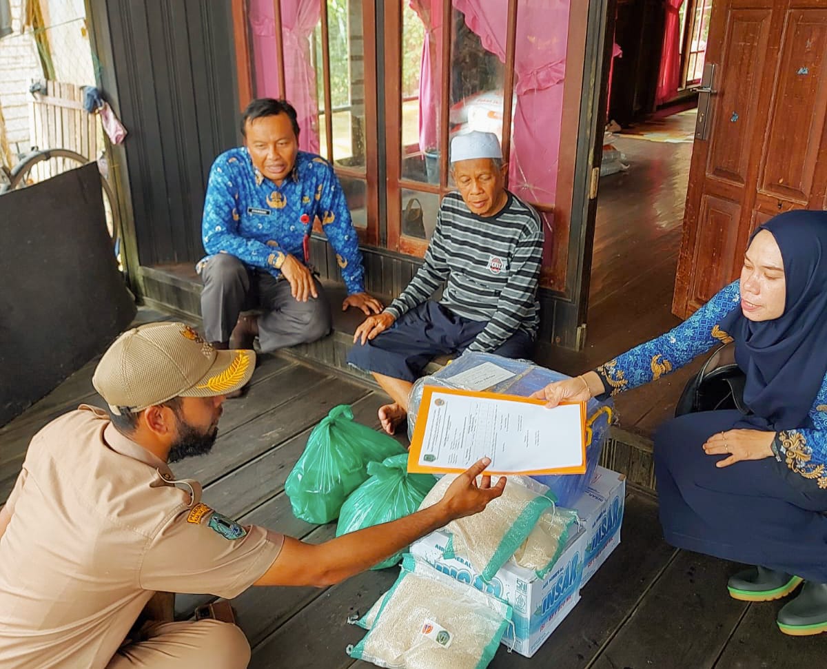PEDULI: Misra (60), warga terdampak banjir di Desa Tuhuran Kecamatan Haur Gading, Kabupaten HSU mendapatkan bantuan sembako dari BPBD Kabupaten HSU, Senin (18/12).(Foto: M Akbar/Radar Banjarmasin)