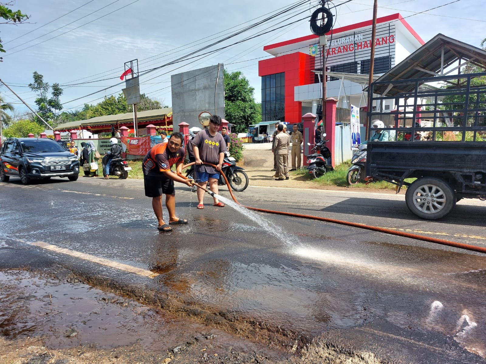 SEMPROT AIR: Relawan BPK Palam Pelaihari bersama Dishub dan Polisi membersihkan ceceran solar di Jalan A Yani, Kelurahan Sarang Halang, Selasa (16/1/2024).(Foto: Norsalim Yahya/Radar Banjarmasin)