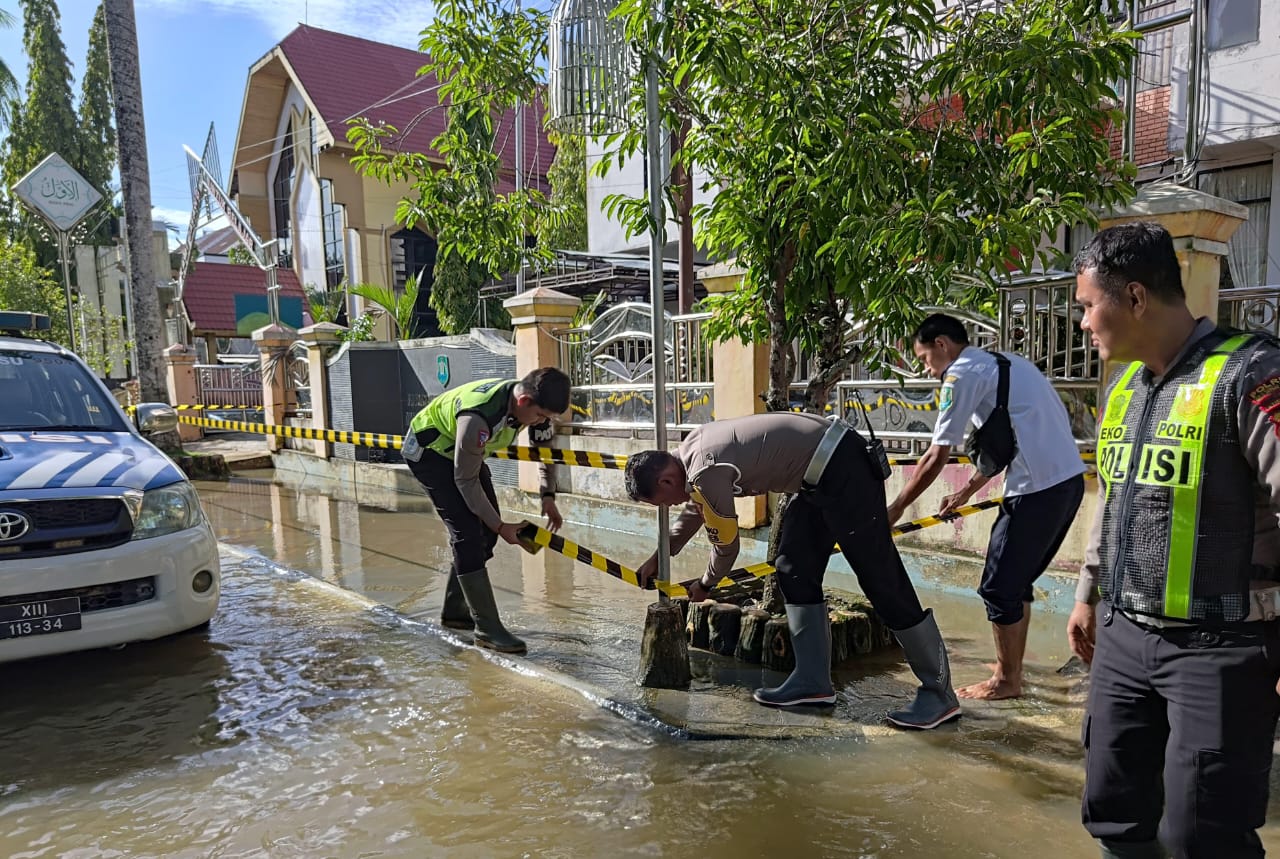 WASPADA: Anggota Satlantas Polres HSU memasang garis Polisi pada drainase yang tertutup banjir di Jalan Ahmad Yani, Kota Amuntai, Rabu (17/1/2024).(Foto: M Akbar/Radar Banjarmasin)
