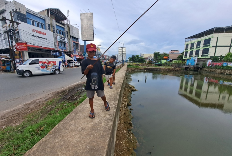 MENUNGGU DIBENAHI: Anak-anak bermain dan memancing di atas siring Sungai Veteran, Banjarmasin Tengah.