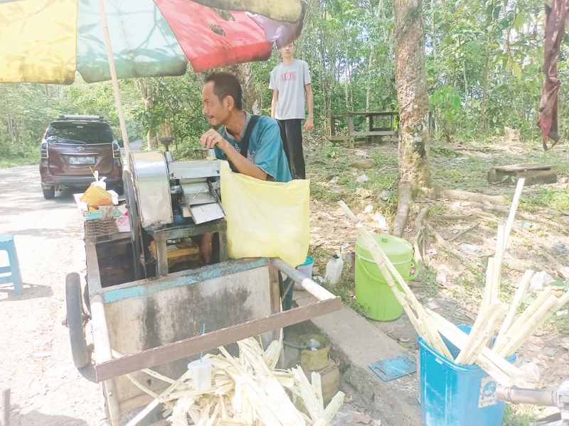 SEMANGAT: Kamarudin melayani pembeli es tebunya di tepi jalan menuju bendungan Pitap.