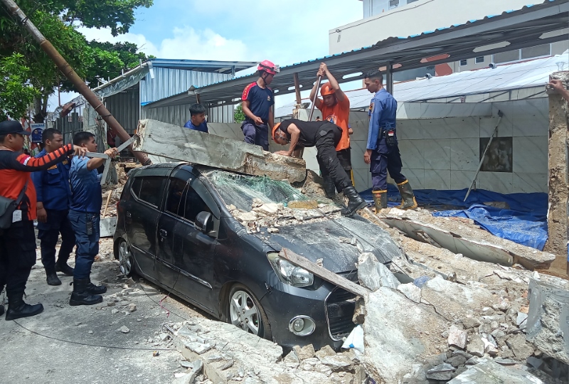 EVAKUASI: Personel gabungan dari DPKP dan BPBD Banjarmasin mengevakuasi mobil yang tertimbuhan reruntuhan tembok beton di Teluk Tiram Laut, Kamis (8/2).