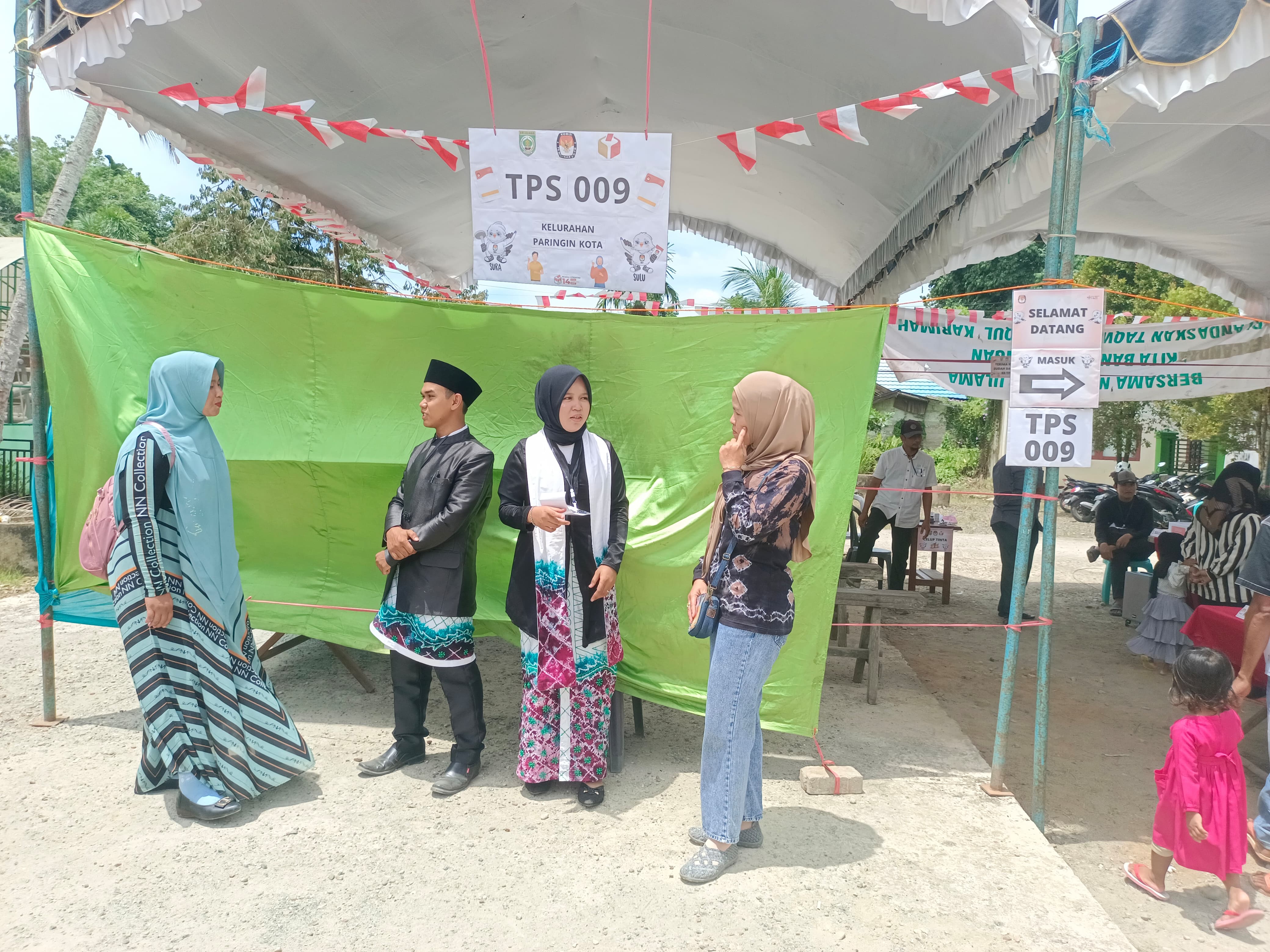 KOSTUM KHUSUS: Petugas TPS 009, Desa Teluk Keramat, Kabupaten Balangan memberikan arahan kepada warga yang ingin mencoblos, Rabu (12/2/2024).(foto: M Dirga/Radar Banjarmasin)