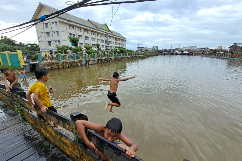 MANDI BERENANG: Anak-anak bermain di Teluk Kelayan dekat rusunawa, Rabu (21/2). Rumah susun sewa itu dibangun Kementerian PUPR pada tahun 2018 lalu.