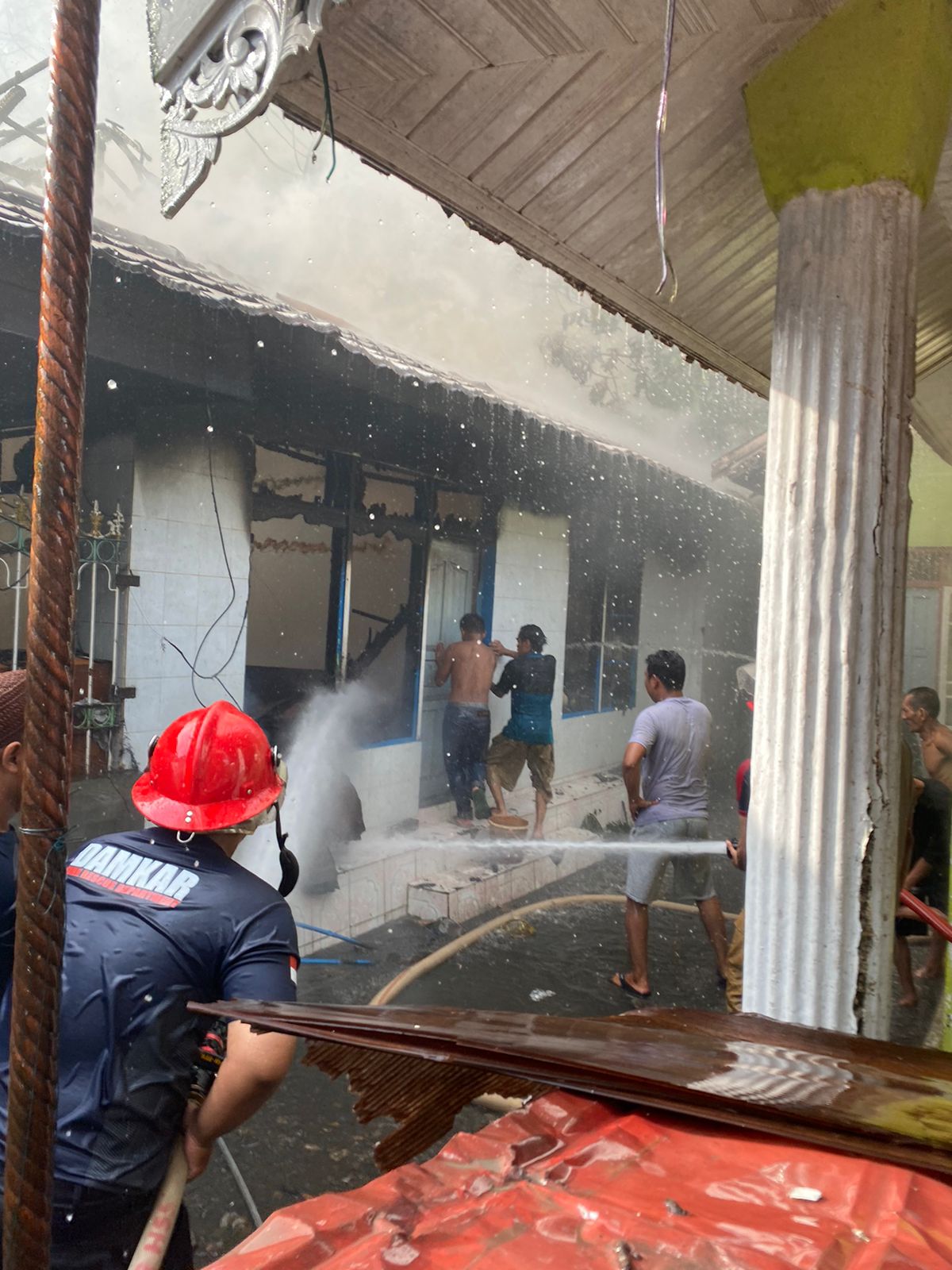 SEMPROT AIR: Relawan BPK memadamkan api yang membakar sebuah rumah di Desa Bakarung, Kecamatan Angkinang, Kabupaten HSS, Minggu (21/4/2024).(Foto:Satpol PP dan Damkar Kabupaten HSS untuk Radar Banjarm