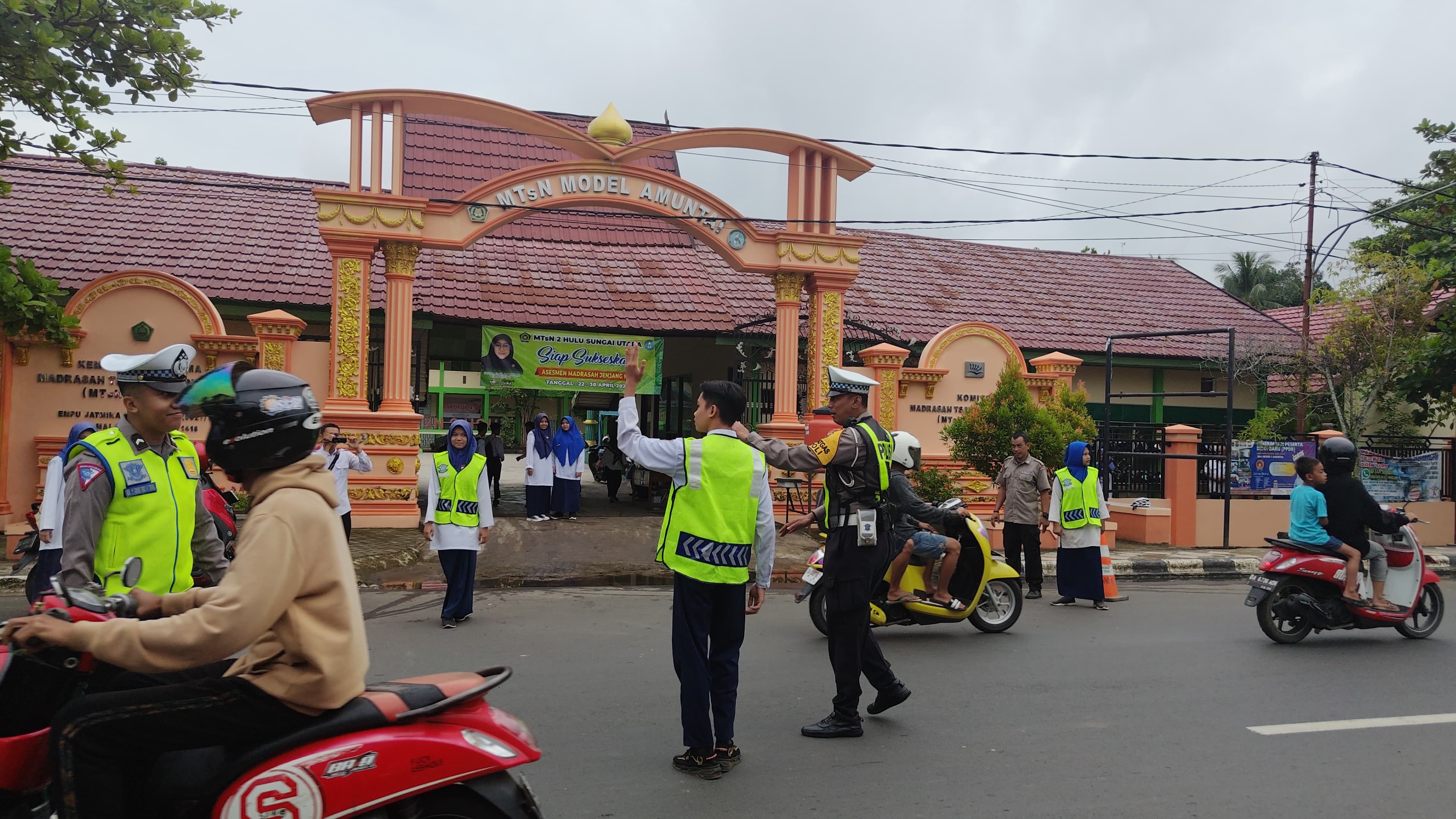 KEGIATAN:Anggota PKS MTsN 2 Amuntai dipandu personel anggota Satlantas Polres HSU, melakukan pengaturan lalin di jam sibuk, Senin (29/4/2024).(Foto: M Akbar/Radar Banjarmasin)