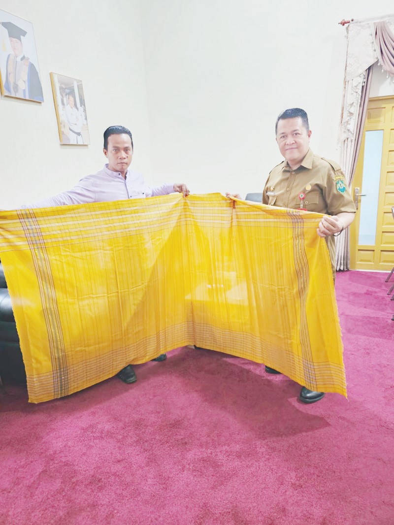PELESTARI: Husain warga Desa Simpang Empat Kecamatan Amuntai Tengah memperlihatkan hasil tenun Sarigading modern ke Sekda HSU Adi Lesmana.
